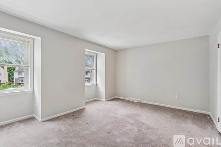 A room with a carpeted floor and two windows.