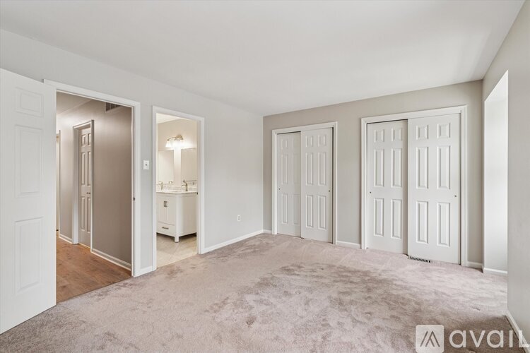 A spacious room with white doors and a carpeted floor.