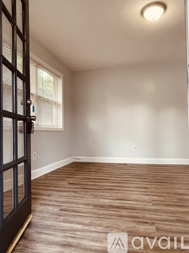 A room with wooden flooring and a window with blinds.