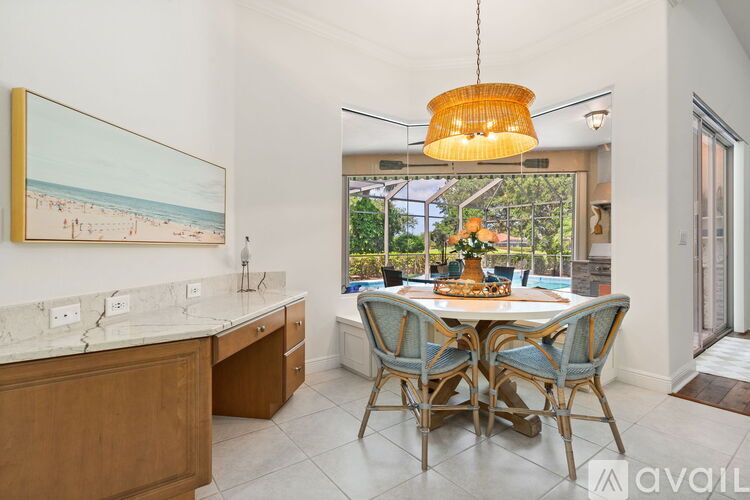 A dining room with a table set for four and a painting of a beach scene on the wall.