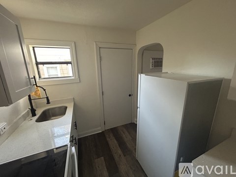 A kitchen with a sink, a window, and a refrigerator.