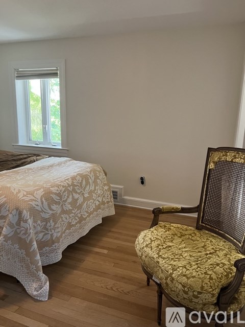 A bedroom with a bed and a chair.