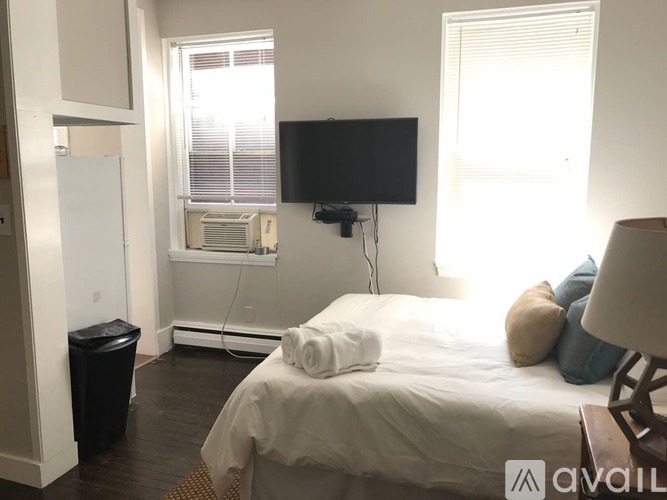 A bedroom with a bed, a television, and a window with blinds.