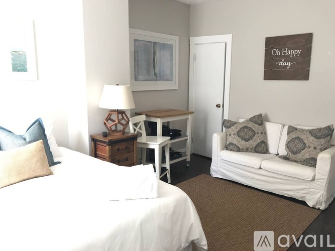 A well-lit bedroom with a bed, couch, and a lamp.