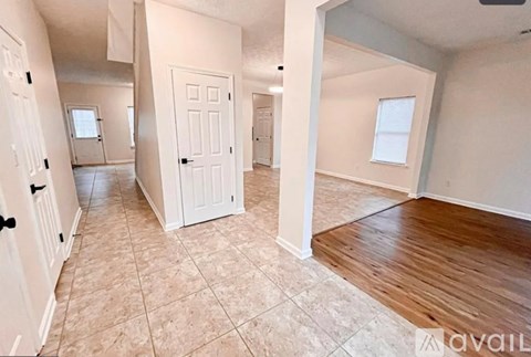 A spacious room with a wooden floor and tiled walls.