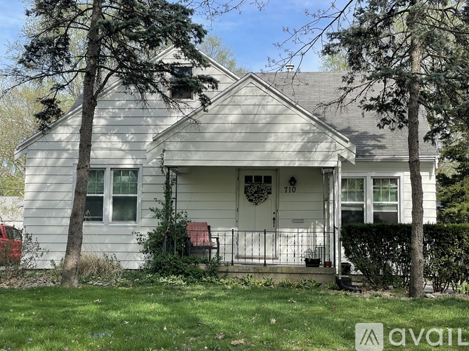 A house with a porch and a tree in front of it.