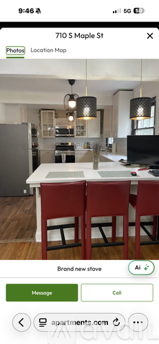 A kitchen with a white table and red chairs.