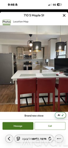 A kitchen with a white table and red chairs.