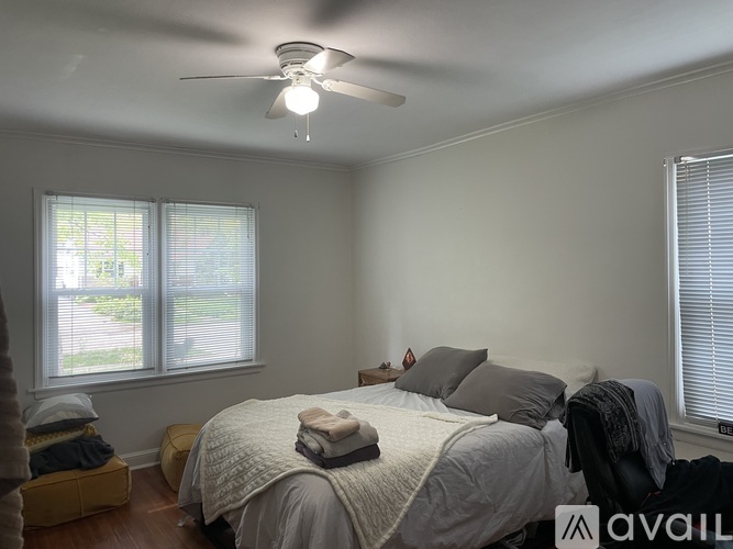A bedroom with a bed, pillows, and a ceiling fan.