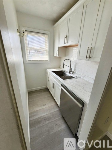 A kitchen with white cabinets and a marble countertop.