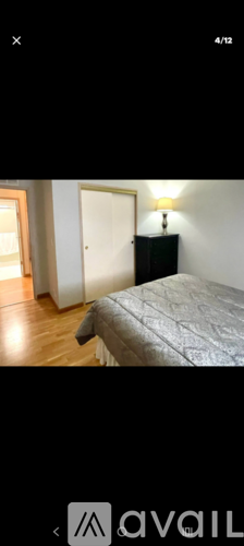 A bedroom with a bed and a lamp on a black cabinet.
