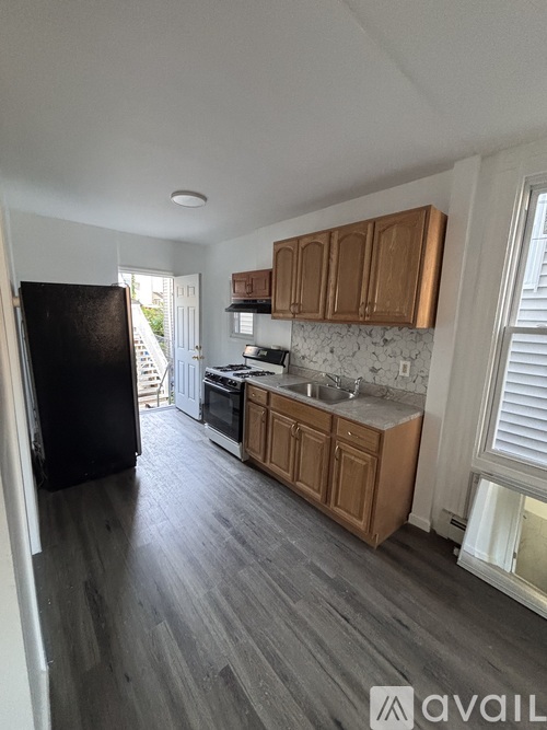 A kitchen with wooden cabinets and a black refrigerator.