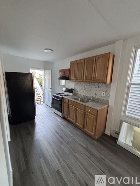 A kitchen with wooden cabinets and a black refrigerator.