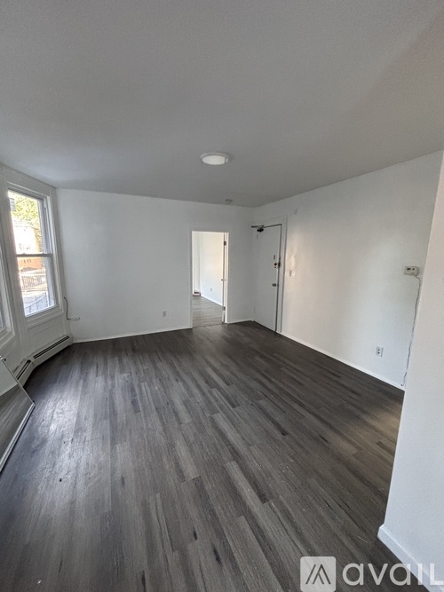 A room with wooden flooring and white walls.