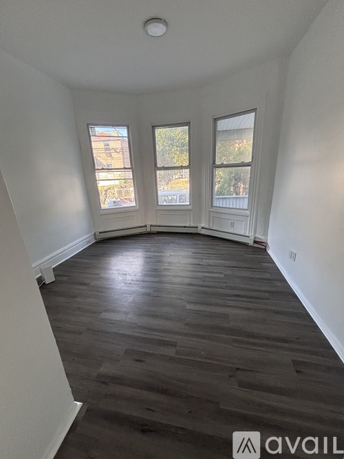 A room with wooden floors and three windows.