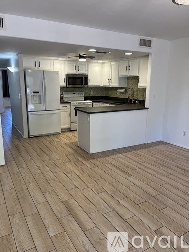 A kitchen with white cabinets and a wooden floor.