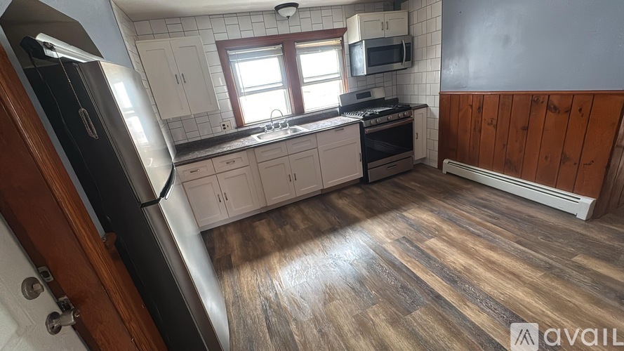 A kitchen with wooden floors and white cabinets is available for rent.