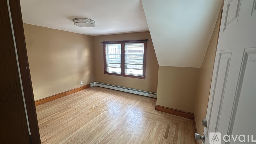 A room with wooden flooring and a window with blinds.