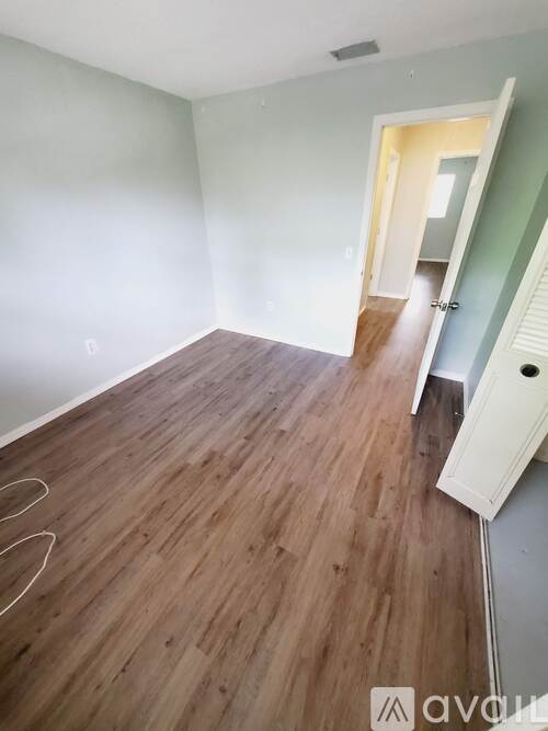A room with wooden flooring and a doorway leading to another room.
