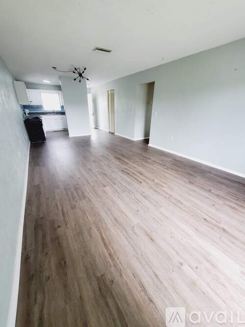 A spacious room with wooden flooring and a ceiling fan.