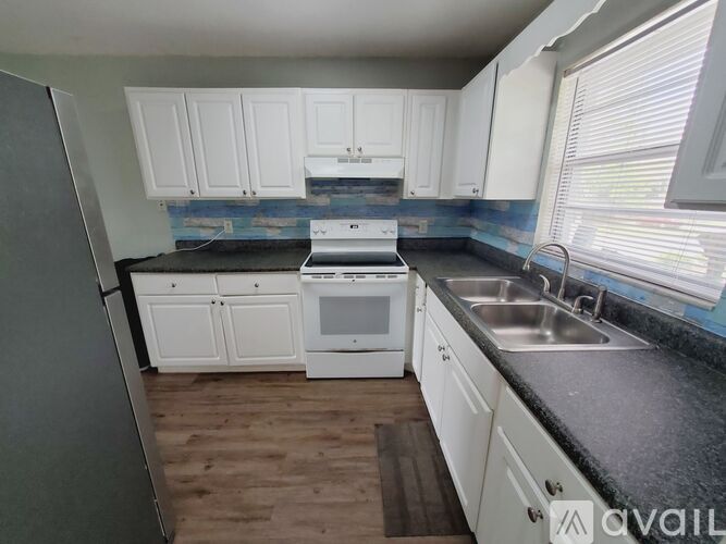 A kitchen with white cabinets and a black countertop.