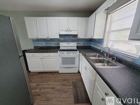 A kitchen with white cabinets and a black countertop.