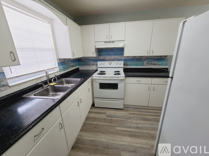 A kitchen with white cabinets and a black countertop.