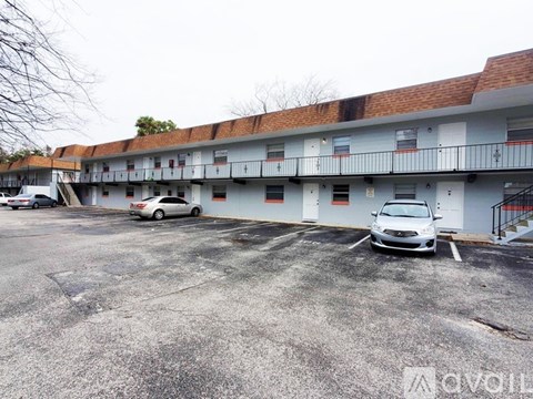 A white car is parked in a parking lot in front of a building.