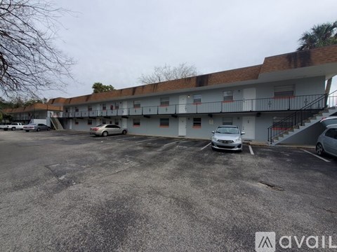 A parking lot with a building in the background and a car parked in the lot.