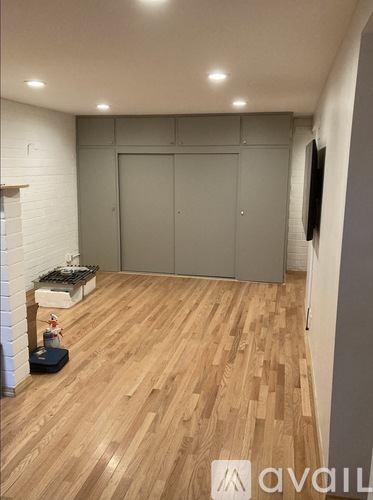 A room with wooden flooring and a white brick wall.