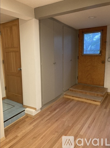 A room with wooden floors and a window with a view of trees outside.