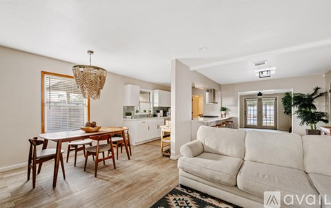 A living room with a white couch and wooden chairs.