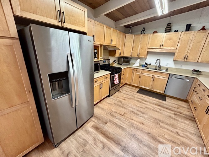 A kitchen with wooden cabinets and a stainless steel refrigerator.