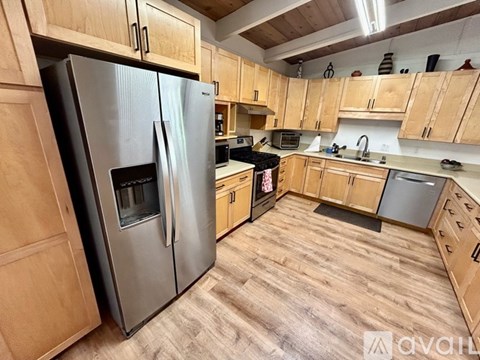 A kitchen with wooden cabinets and a stainless steel refrigerator.