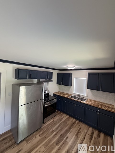 A kitchen with a stainless steel refrigerator and black cabinets.