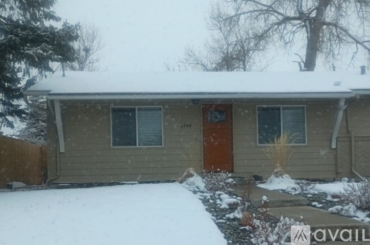 A house with a brown door and windows is covered in snow.