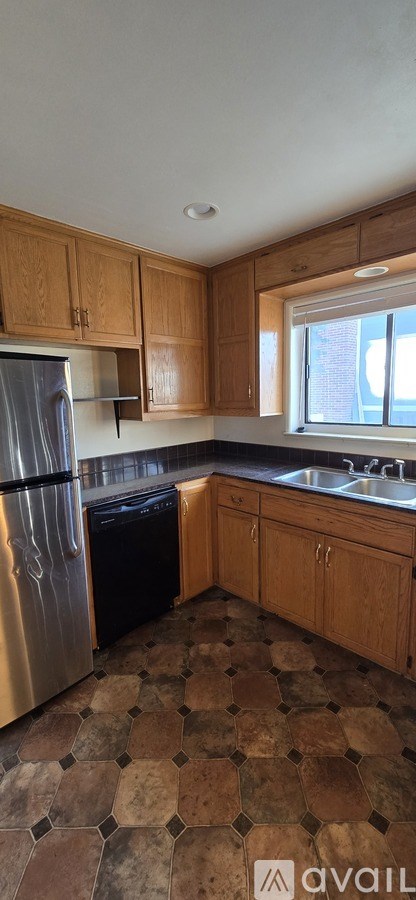 A kitchen with wooden cabinets and a tiled floor.