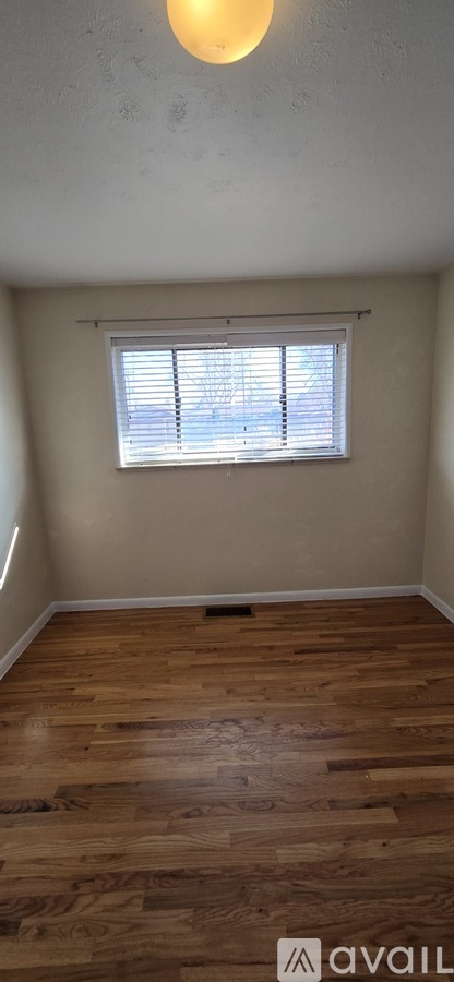 A room with wooden flooring and a window with blinds.