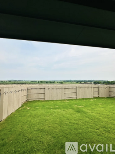 A backyard with a wooden fence and green grass.