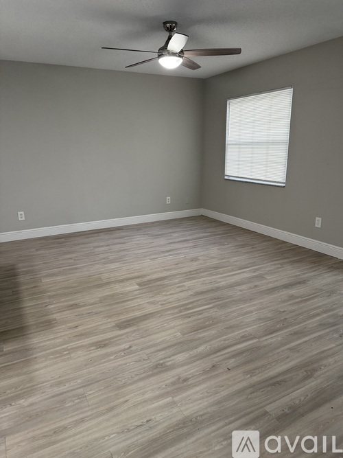 A room with a ceiling fan and wooden flooring.