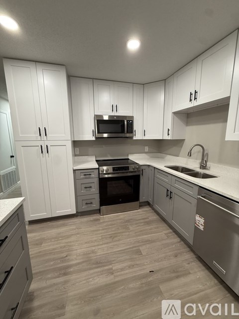 A kitchen with white cabinets and a wooden floor.