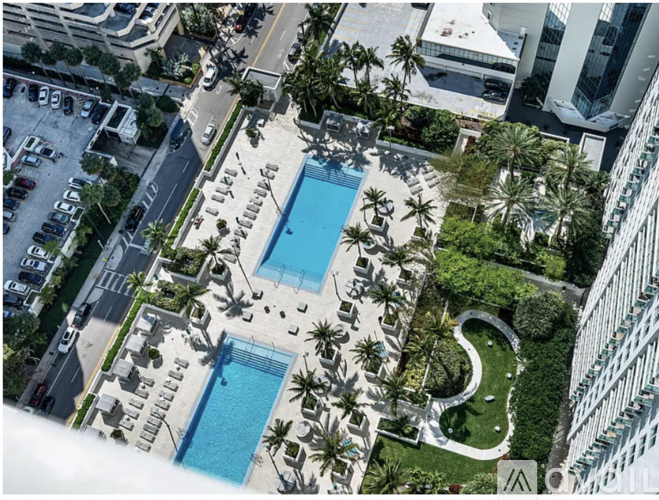A large swimming pool surrounded by palm trees and a white fence.