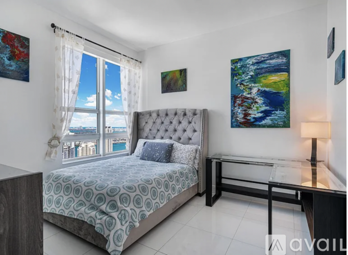 A bedroom with a large bed and a painting on the wall.