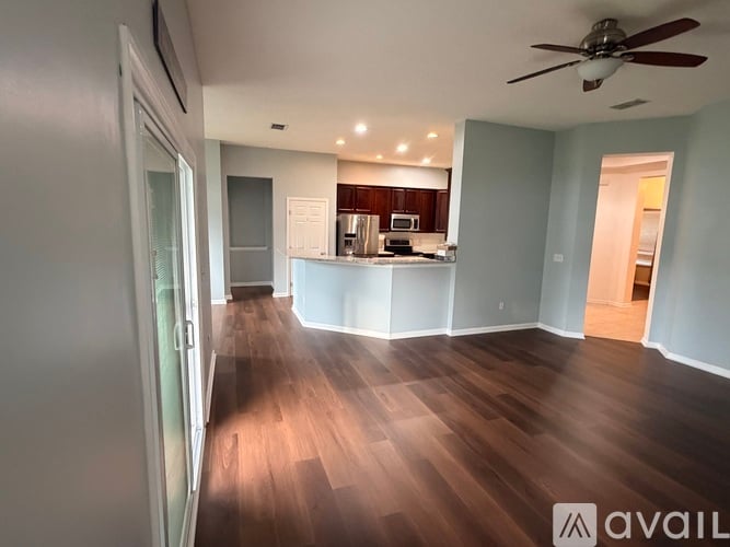 A spacious room with wooden flooring and a ceiling fan.