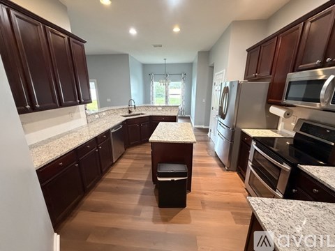 A kitchen with dark brown cabinets and a marble countertop.