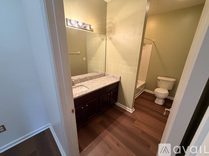 A small bedroom with a bed, toilet, and wooden floors.