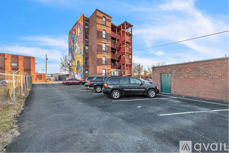 A parking lot with cars and a tall building with a mural on it.