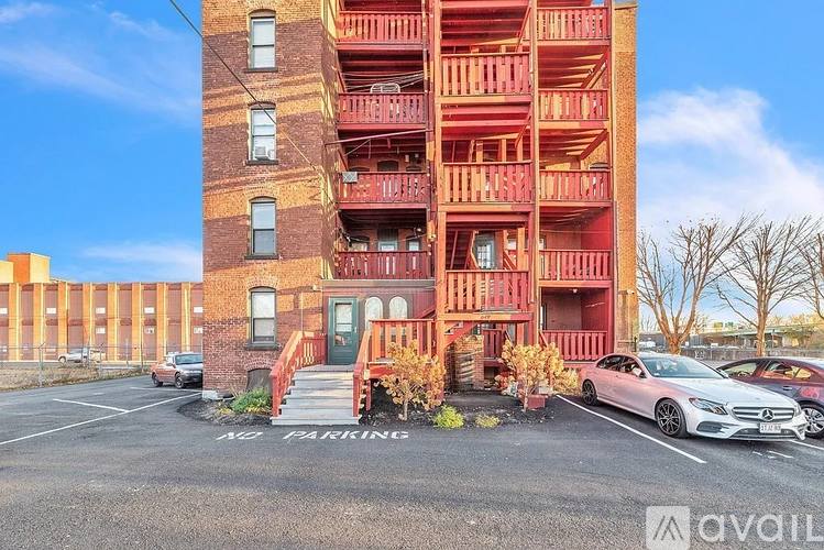 A tall red brick building with a parking lot in front of it.