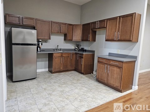 A kitchen with wooden cabinets and a stainless steel refrigerator.