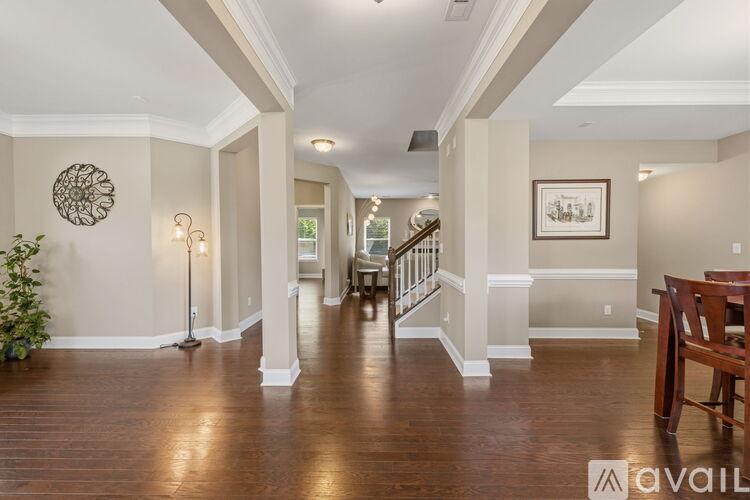 A spacious hallway with wooden floors and white walls.